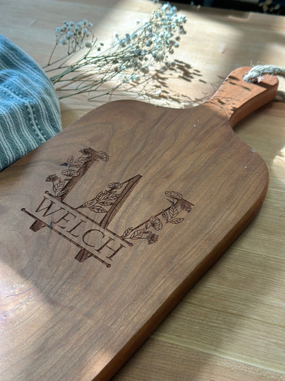 Wooden charcuterie board with engraved design on a wooden surface.