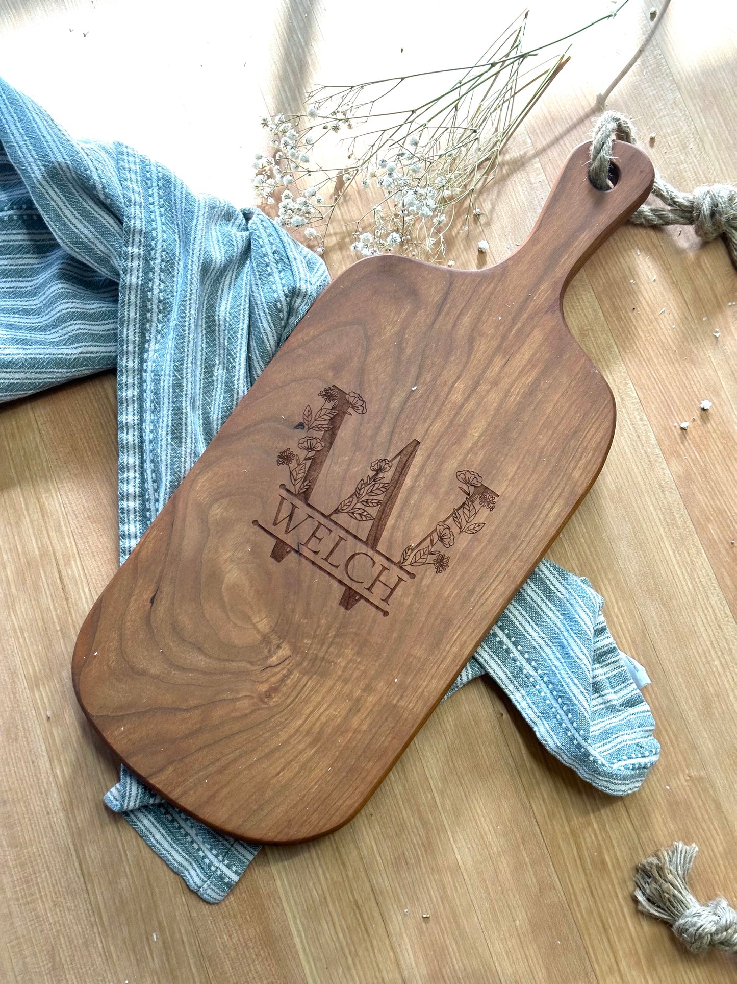 Wooden serving board with 'Welch' engraving on a wooden surface with a blue cloth.